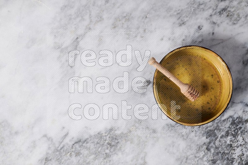 Multicolored Pottery Oven Plate with wooden honey handle in it, on grey marble flooring, Top View