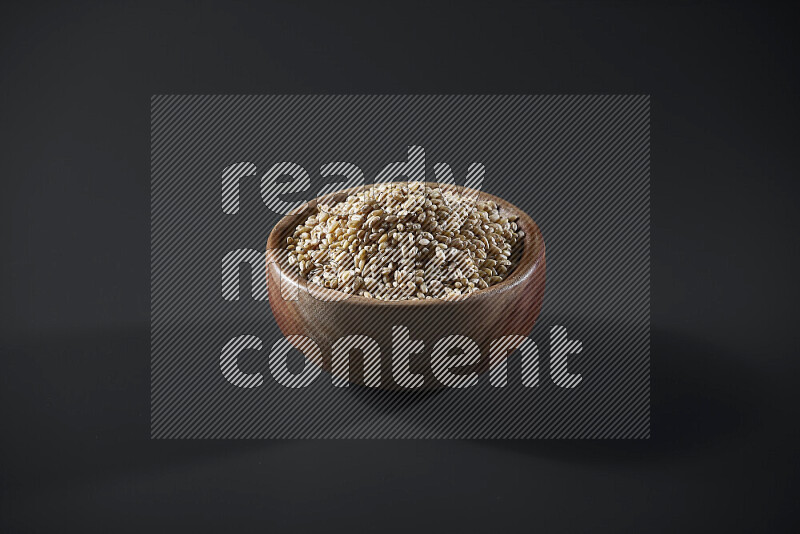 Hulled wheat in a wooden bowl on grey background