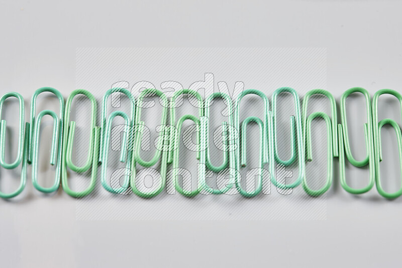 Green paperclips isolated on a grey background