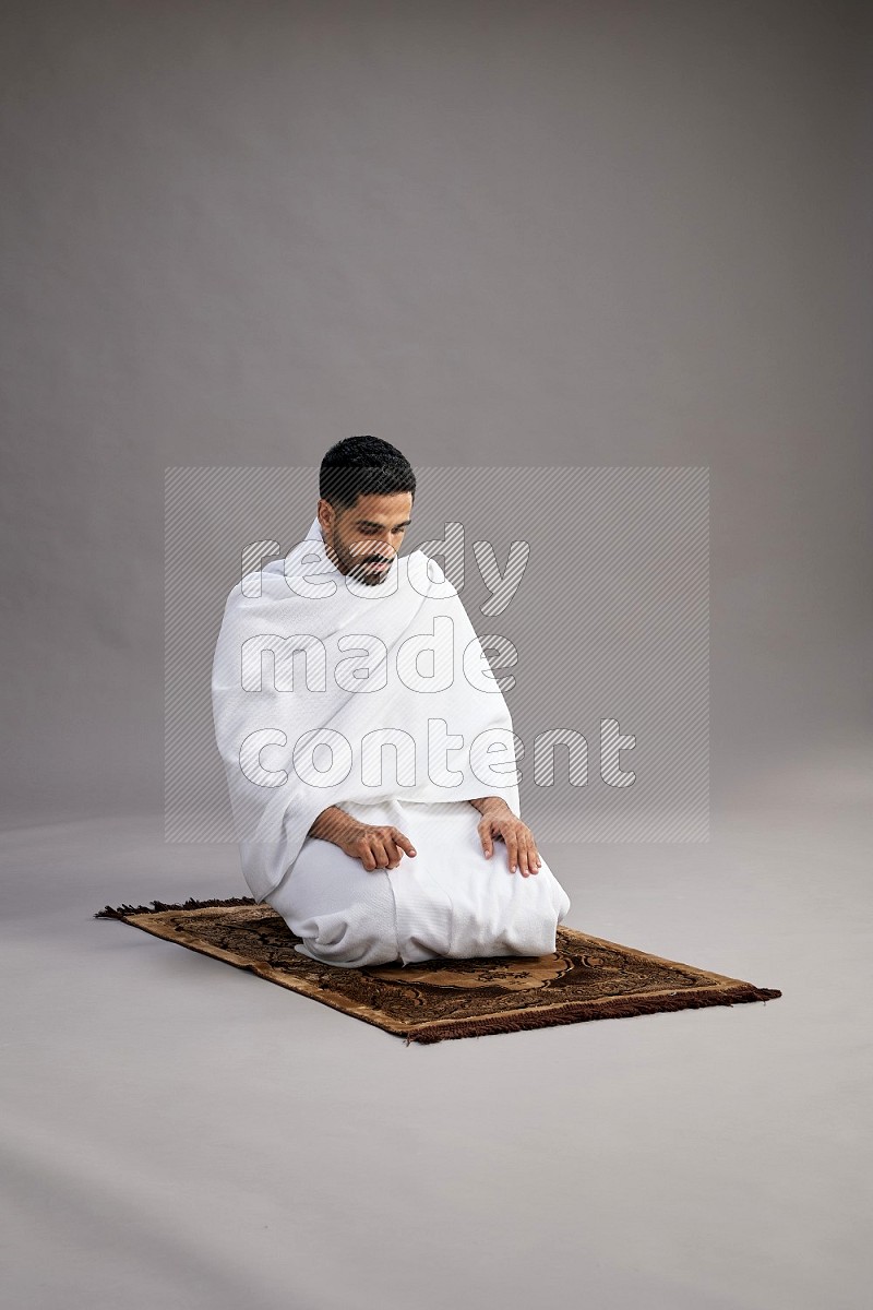 A man wearing Ehram praying on gray background