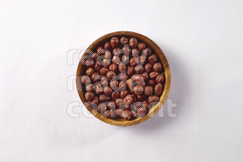 Hazelnuts in a wooden bowl on white background