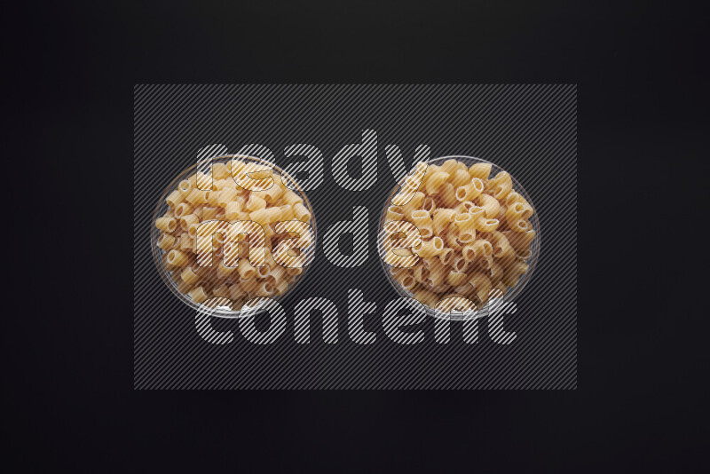 أنواع مختلفة من المعكرونة في وعاء زجاجي علي خلفية سوداء