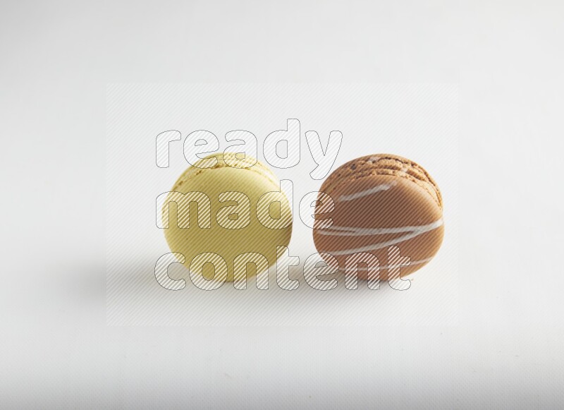 45º Shot of of two assorted Brown Irish Cream, and Yellow Lime macarons on white background