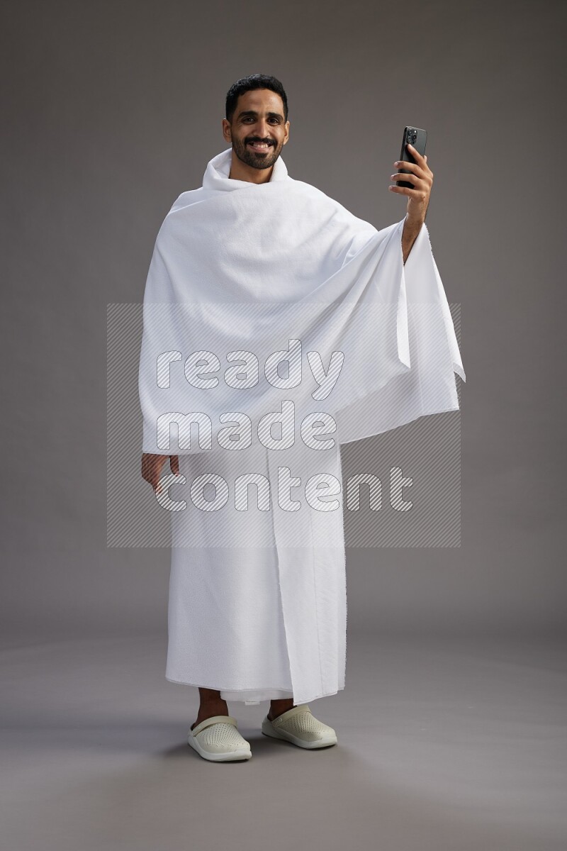 A man wearing Ehram Standing taking selfie on gray background