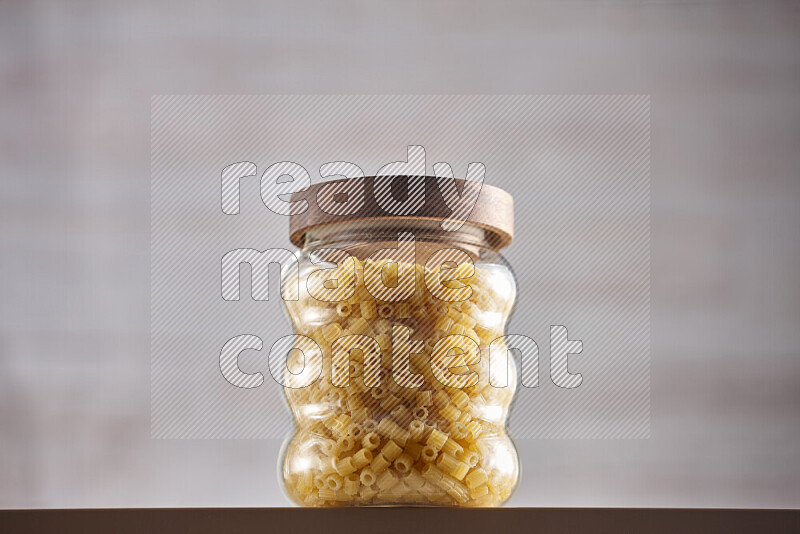 Raw pasta in glass jars on beige background