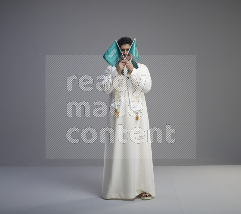 رجل سعودي يرتدي ثوب ابيض ويحمل علم السعودية