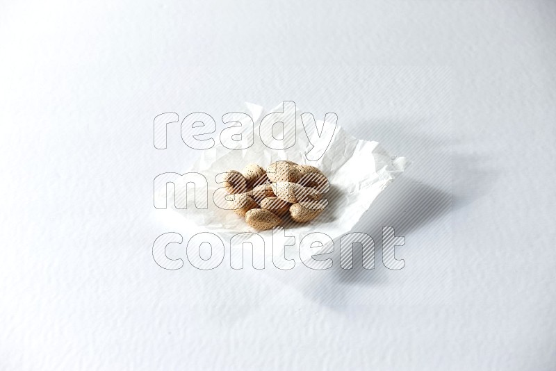Almonds on a crumpled piece of paper on a white background in different angles