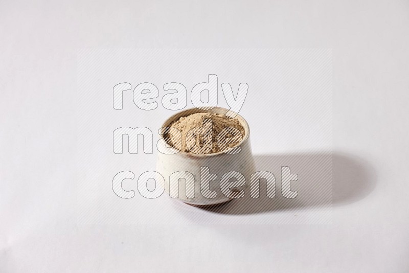 A beige pottery bowl full of garlic powder on a white flooring in different angles