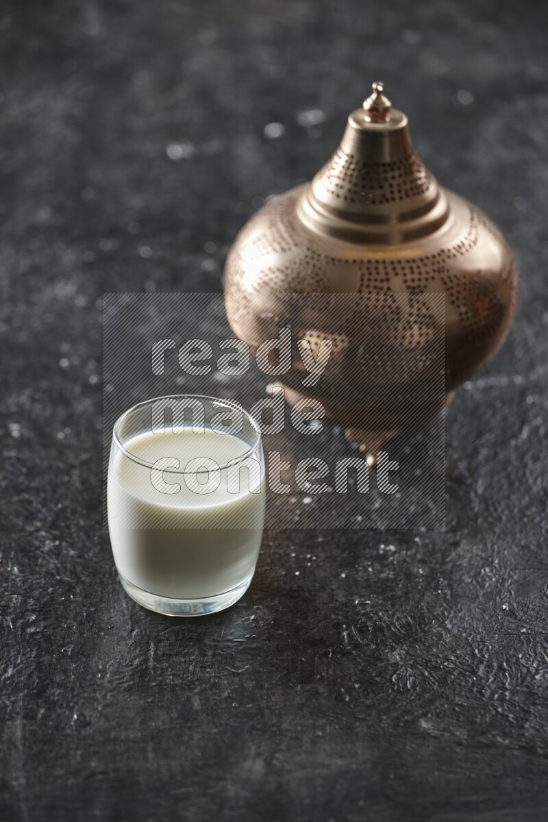 A golden lantern with different drinks, dates, nuts, prayer beads and quran on textured black background