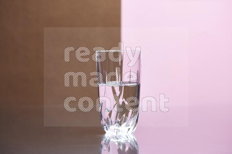The image features a clear glassware filled with water, set against brown and rose background