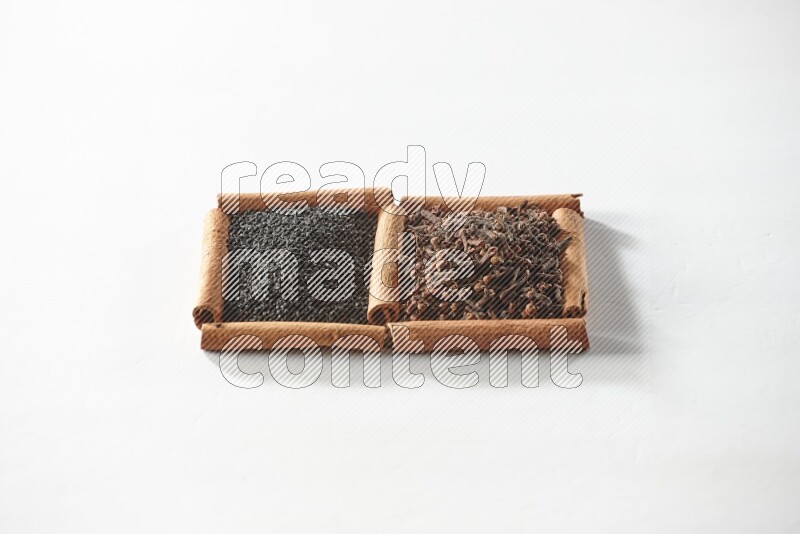 2 squares of cinnamon sticks full of cloves and black seeds on white flooring