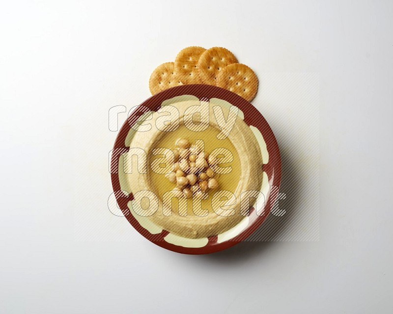 Hummus in a traditional plate garnished with roasted chickpeas  on a white background