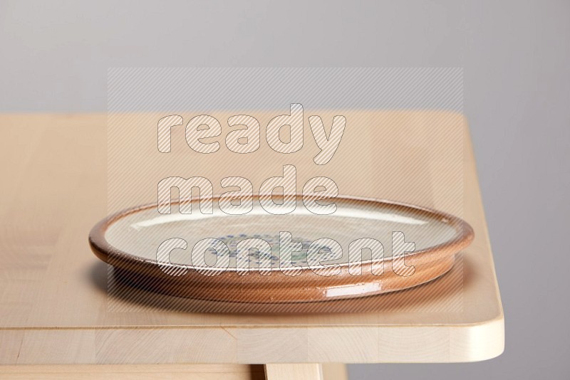 multi-colored pottery Plate on a wooden table edge