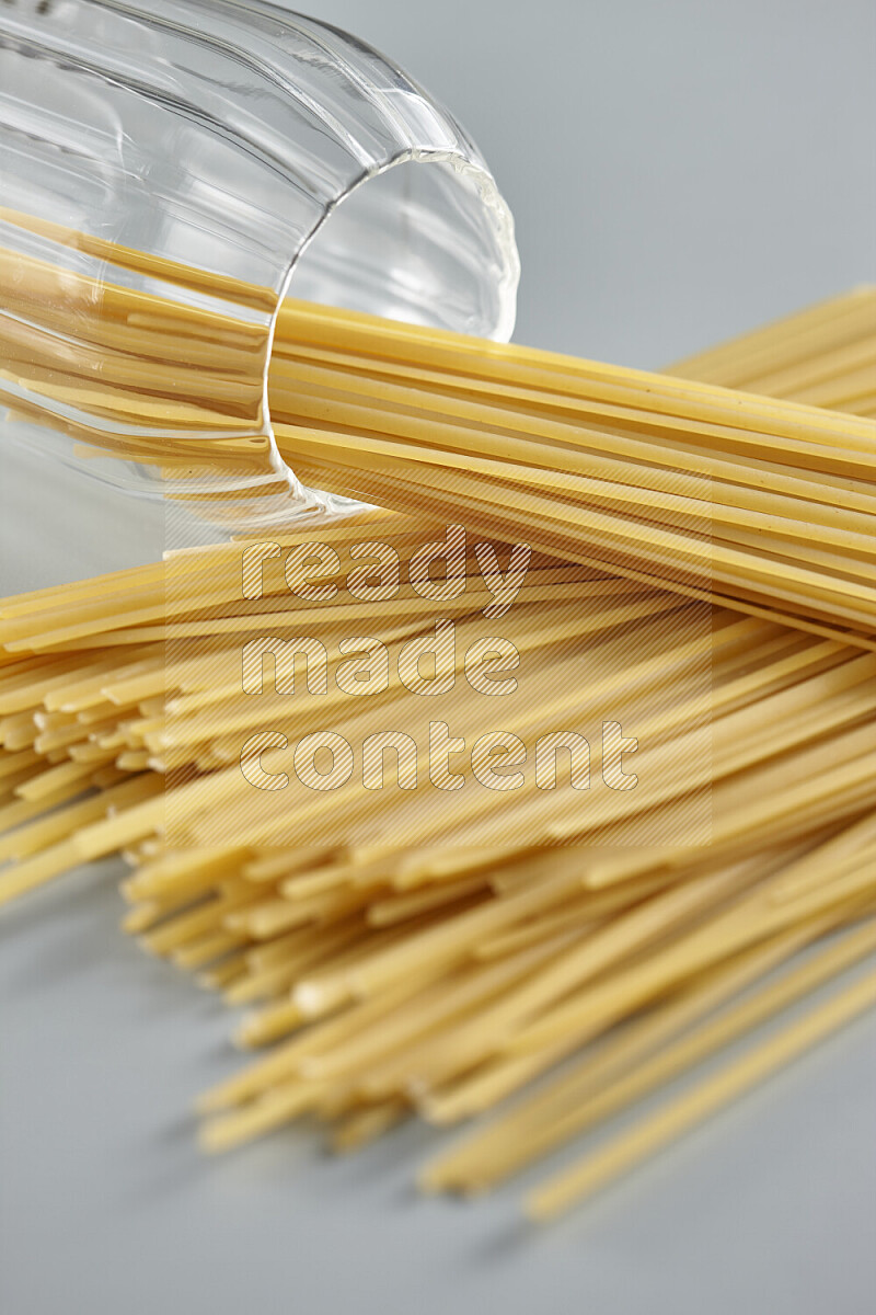 Flipped jar full of raw pasta on light blue background