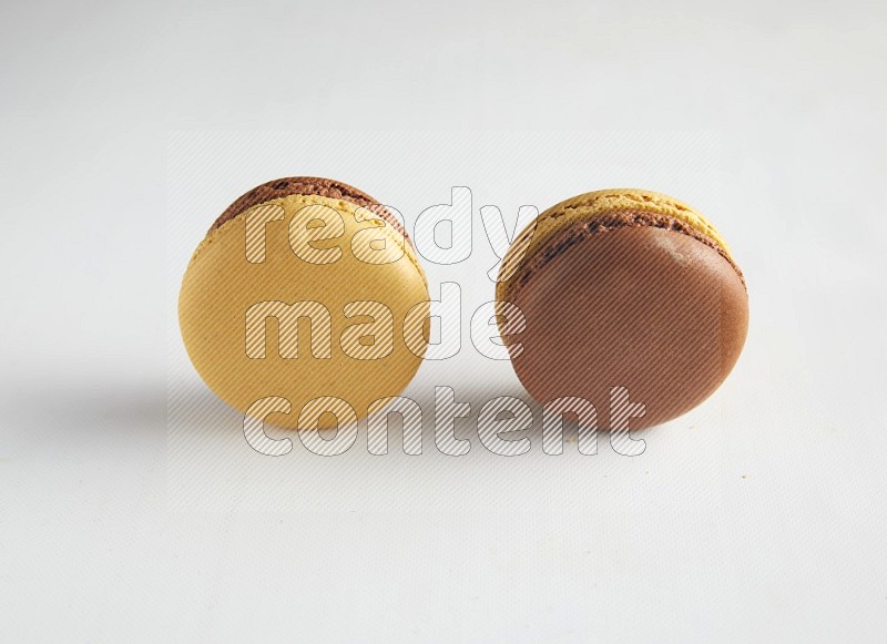 45º Shot of two Yellow and Brown Chai Latte macarons on white background