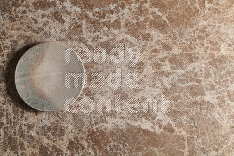 A multicolored pottery plate on beige marble background