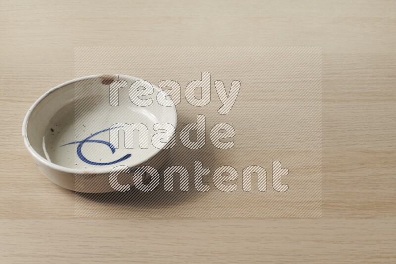 A multicolored pottery bowl on light wooden background