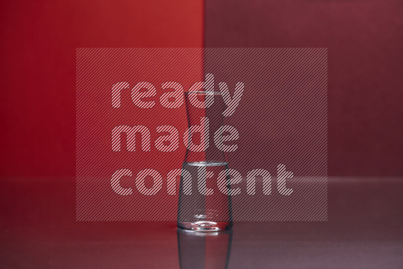 The image features a clear glassware filled with water, set against red and dark red background