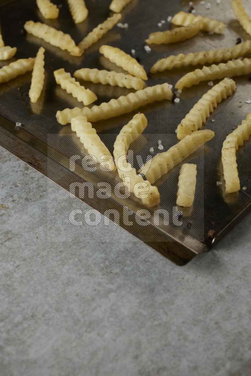 crinkle fries in a black stainless steel rectangle tray on grey textured counter top