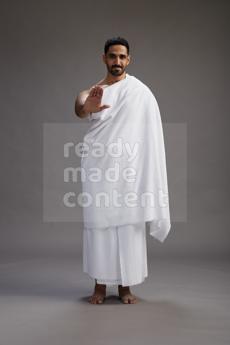 A man wearing Ehram Standing Interacting with the camera on gray background