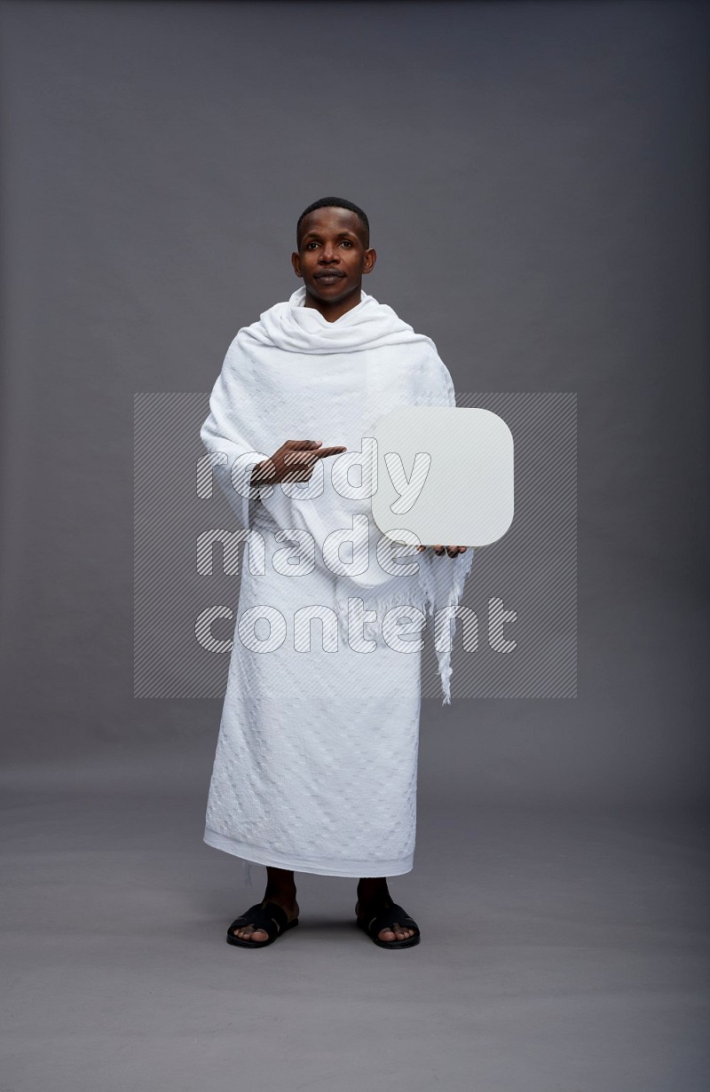 A man wearing Ehram Standing holding social media sign on gray background