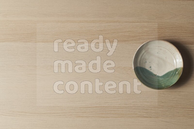 A multicolored pottery plate on light wooden background