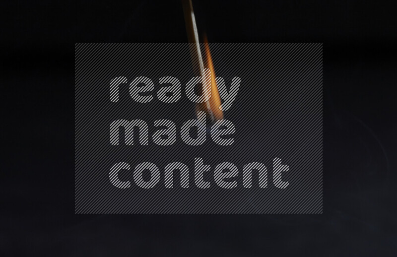 A burning matchstick isolated on dark backdrop