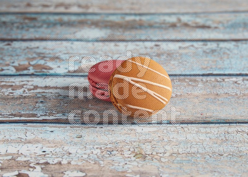 45º Shot of of two assorted Brown Irish Cream, and Pink Raspberry macarons on light blue background