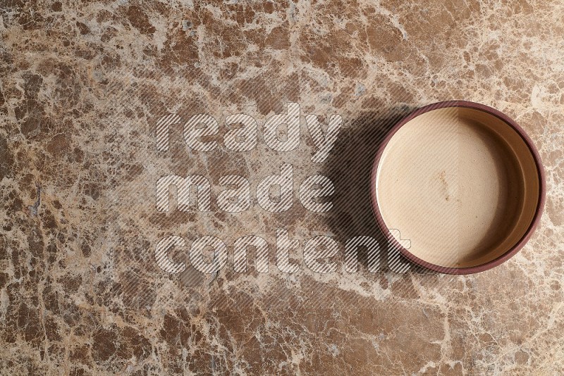 Top View Shot Of A Beige Pottery Oven Plate On beige Marble Flooring