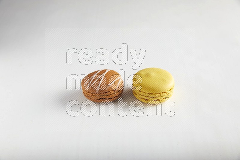 45º Shot of of two assorted Brown Irish Cream, and Yellow Lemon macarons on white background