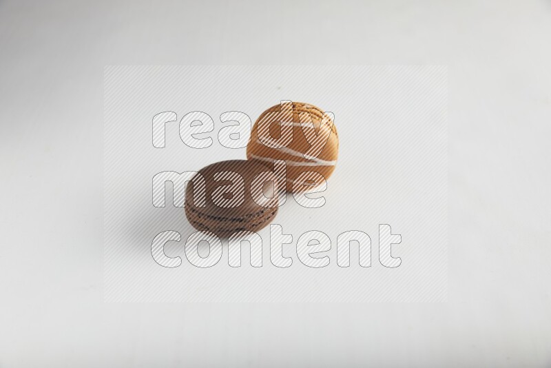 45º Shot of of two assorted Brown Irish Cream, and Brown Dark Chocolate macarons on white background