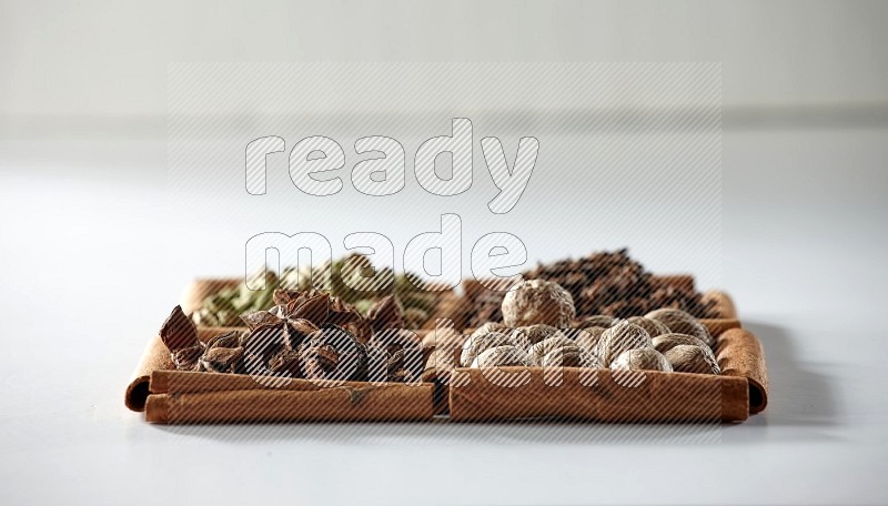 4 squares of cinnamon sticks full of cardamom, star anise, cloves and nutmeg on white flooring