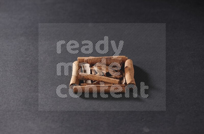 A single square of cinnamon sticks full of cinnamon on black flooring