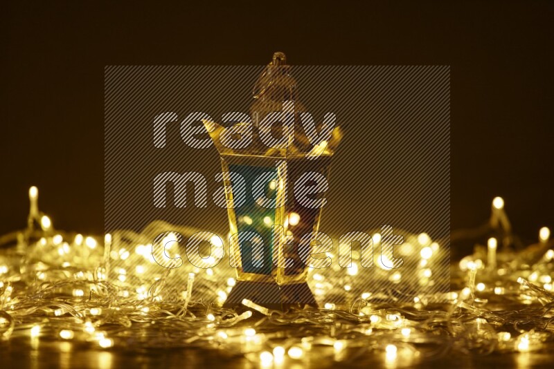 A traditional ramadan lantern surrounded by glowing fairy lights in a dark setup