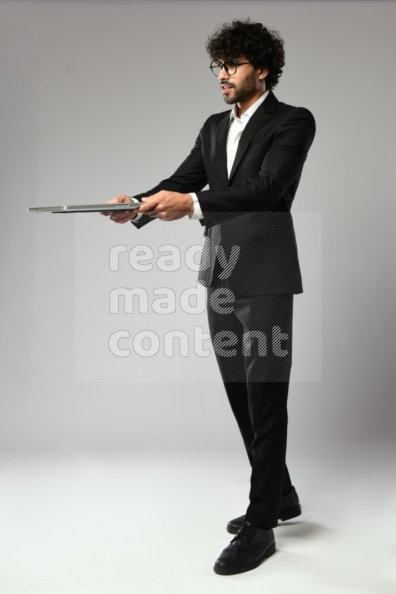 A man wearing formal standing and holding a laptop on white background