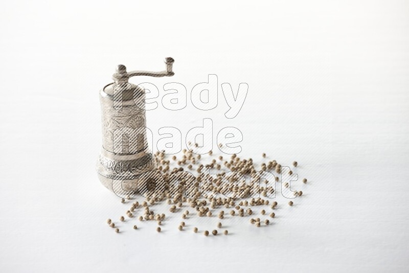 White pepper beads with a metal grinder on white flooring