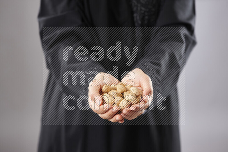 Woman in abaya holding different kinds of nuts in different positions