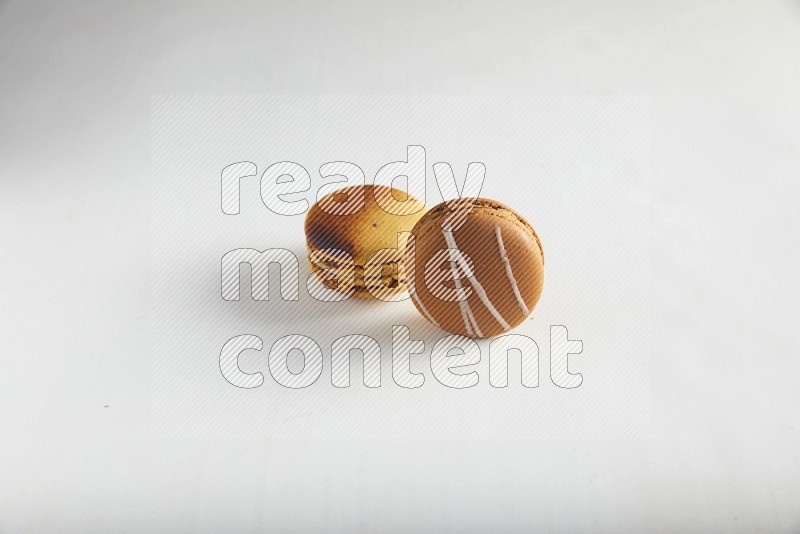 45º Shot of of two assorted Brown Irish Cream, and Yellow Crème Brulée macarons on white background