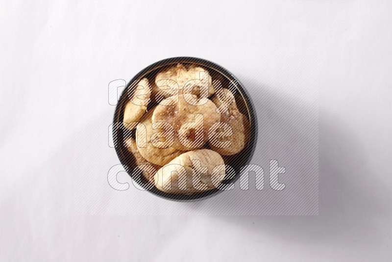 Dried figs in a black pottery bowl on white background