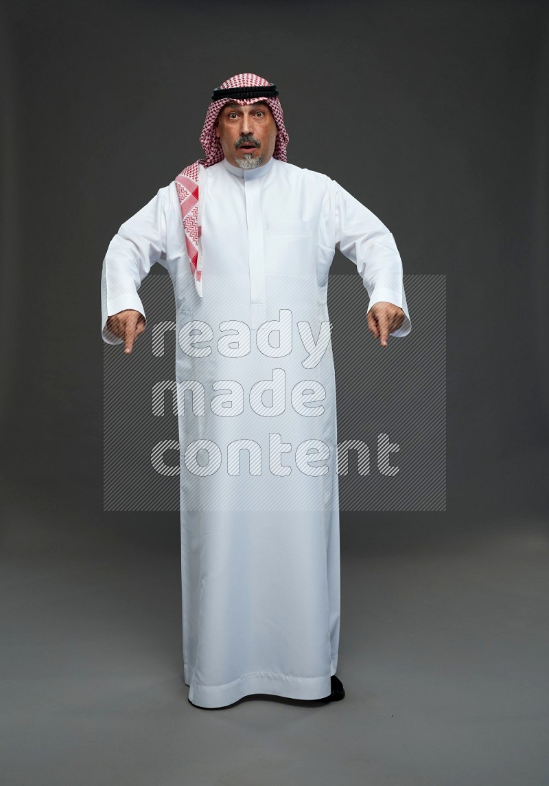 Saudi man with shomag Standing Interacting with the camera on gray background