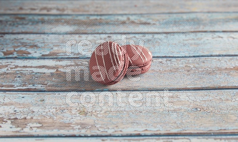 45º Shot of two Red Poppy Flower macarons on light blue wooden background