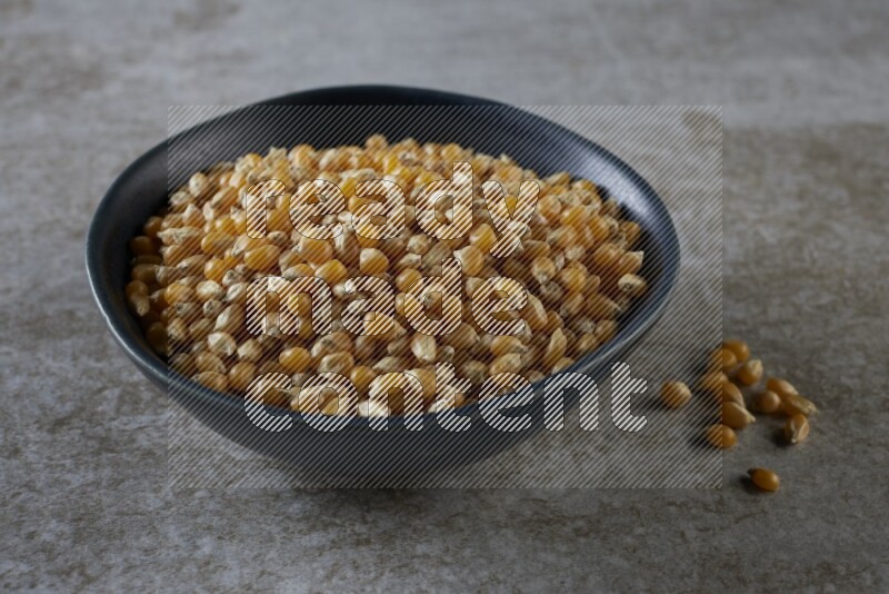 corn kernel in a black ceramic bowl on a grey textured countertop