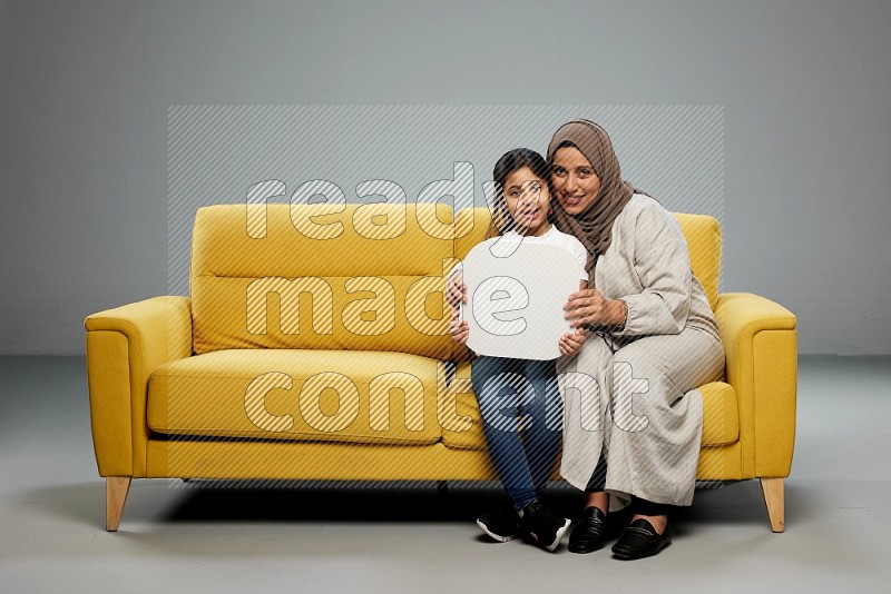Mom and daughter sitting holding social media sign on gray background