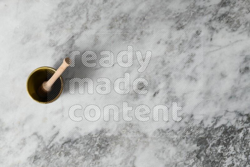 Multicolored pottery cup with wooden honey dipper in it on grey marble background