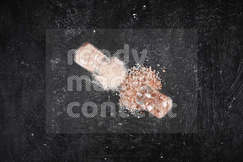 2 glass jars one is filled with fine himalayan salt and the other with coarse himalayan salt on black background