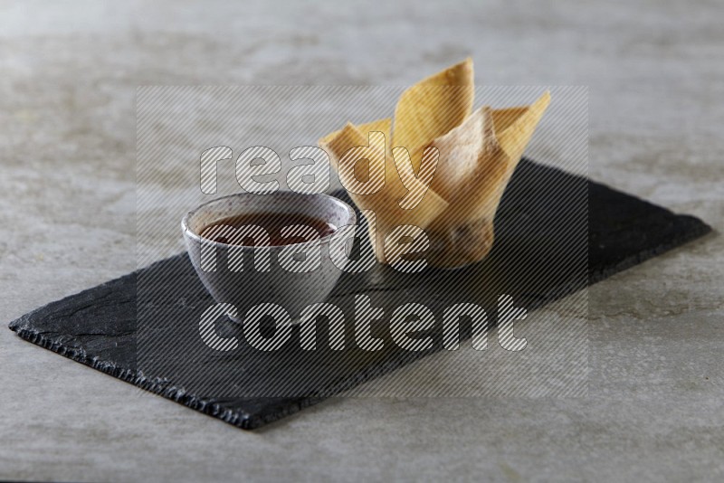 wonton cups with soy sauce ramkin on rectangle slate on grey textured counter top