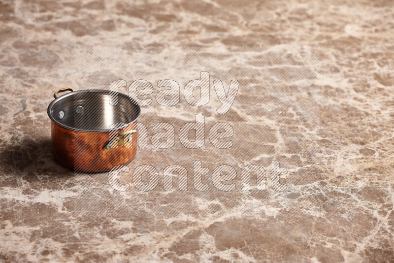 A small copper pot on beige marble background