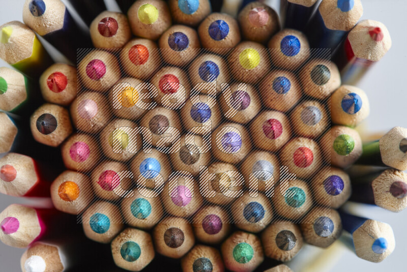 The image captures top view shot of sharpened colored pencils on grey background