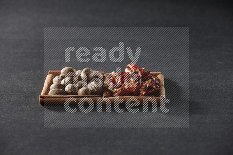 2 squares of cinnamon sticks full of nutmegs and dried red chilis on black flooring