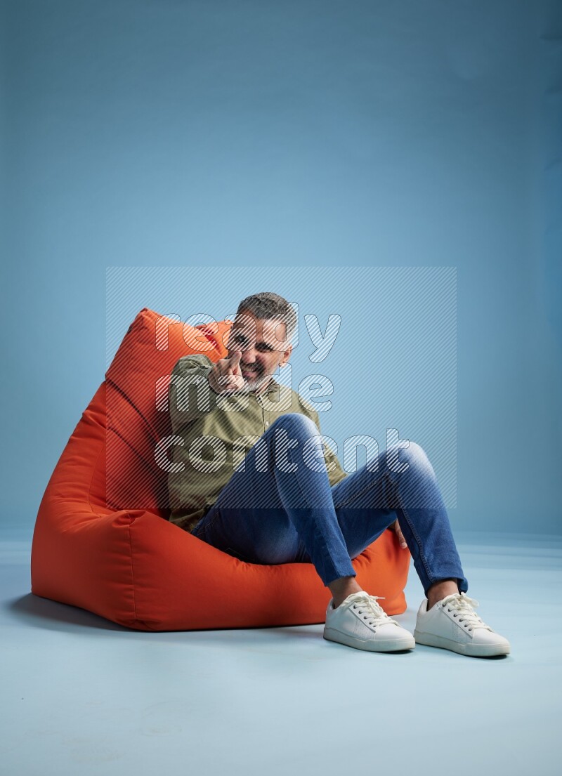 A man sitting on an orange beanbag and interacting with the camera